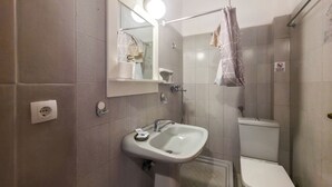 Un baño con lavamanos, espejo, inodoro y cortina de ducha.