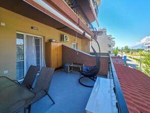 A balcony with a sofa, a chair, a table, and a hanging chair. - 104 - EVROSTAR Studio by SDR (Paralia)