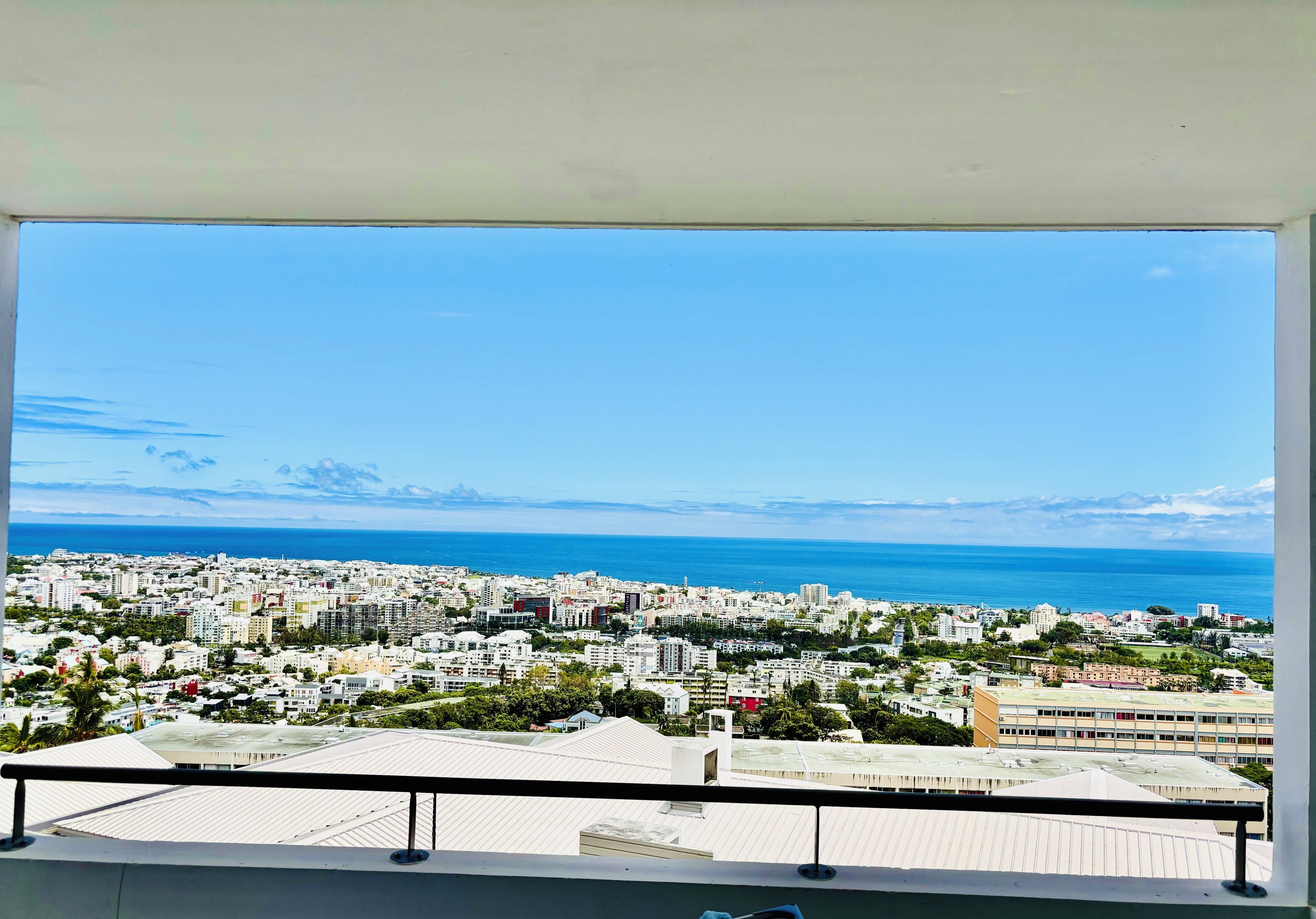 Een balkon met uitzicht op een kuststadsgezicht, gebouwen en de zee.