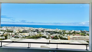 Een balkon met uitzicht op een kuststadsgezicht, gebouwen en de zee.