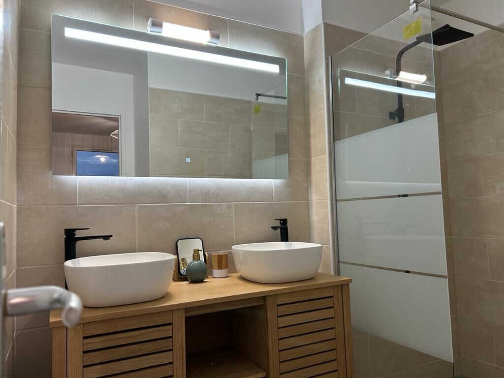 Een moderne badkamer met twee wastafels, een spiegel en een douche.