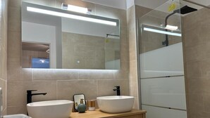 Een moderne badkamer met twee wastafels, een spiegel en een douche.
