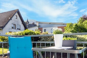 A balcony with a potted plant, a blue cushion, and a metal railing. - Coerdt Apartment in Olsberg with Beautiful Balcony (Olsberg)