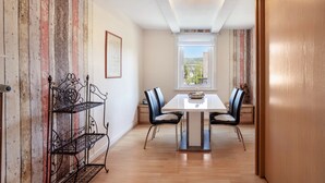 Un comedor con una mesa blanca, sillas negras y un estante de metal.