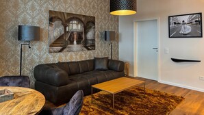 Un salón moderno con sofá, una mesita de centro, pared con estampado y dos lámparas de pared.