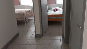 Ein Zimmer mit zwei Betten, einem Fenster und einer Tür.