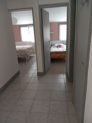 Ein Zimmer mit zwei Betten, einem Fenster und einer Tür.