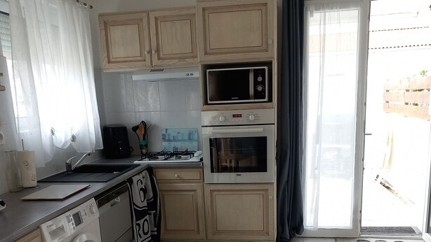 Eine Küche mit Waschmaschine, Mikrowelle, Backofen und einem Essbereich mit einer Couch.