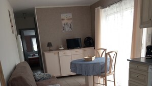 Ein Zimmer mit Bett, Tisch, Stuhl, Fernseher und einer Küchenzeile.