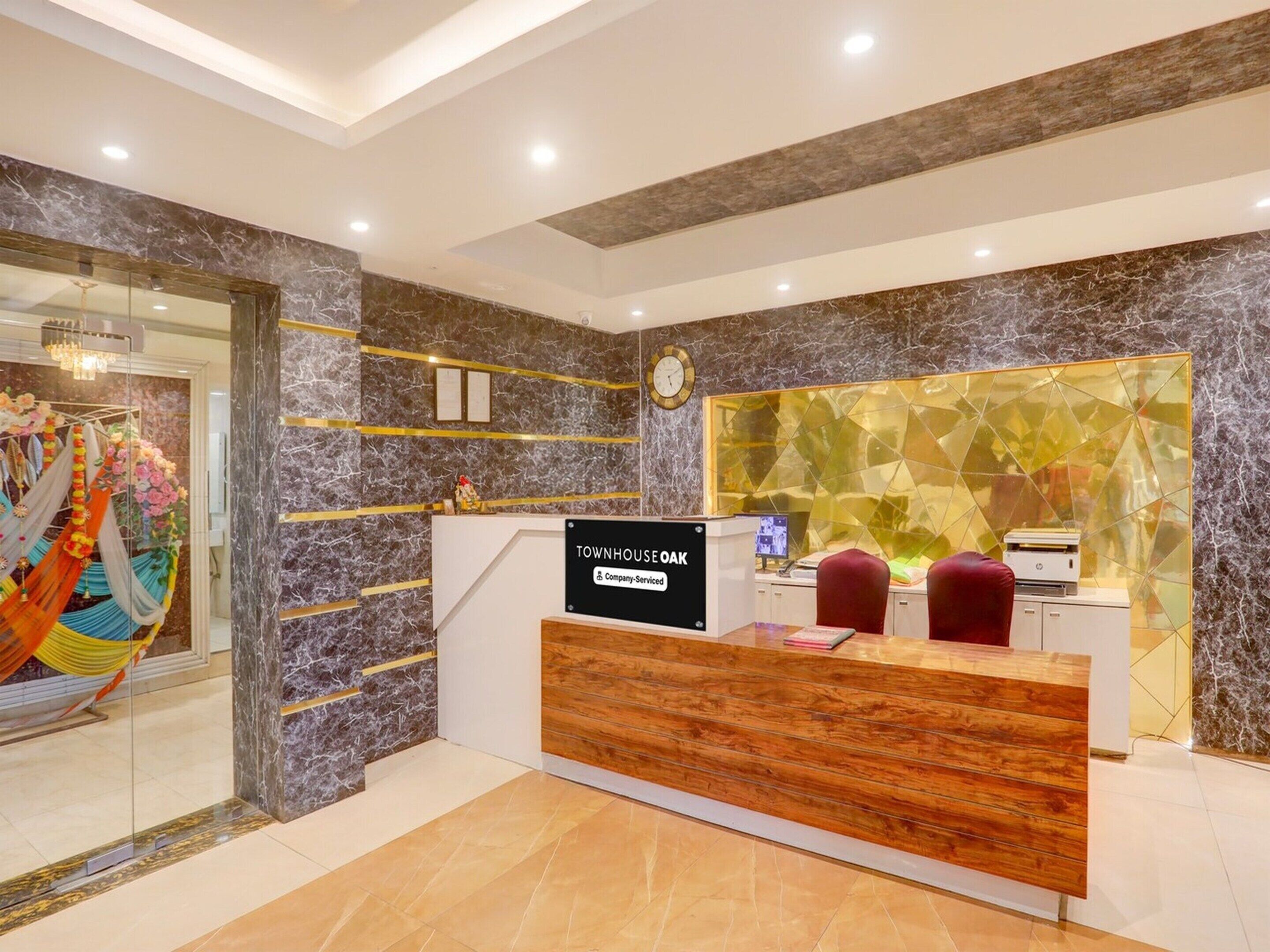 A reception desk with a sign reading 'Townhouse Oak Company Serviced,' a clock, and a reception area with a marble wall and a decorative glass panel.