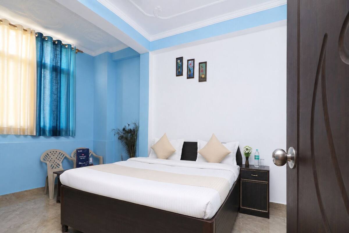A bedroom with a bed, a nightstand, a chair, and a door.
