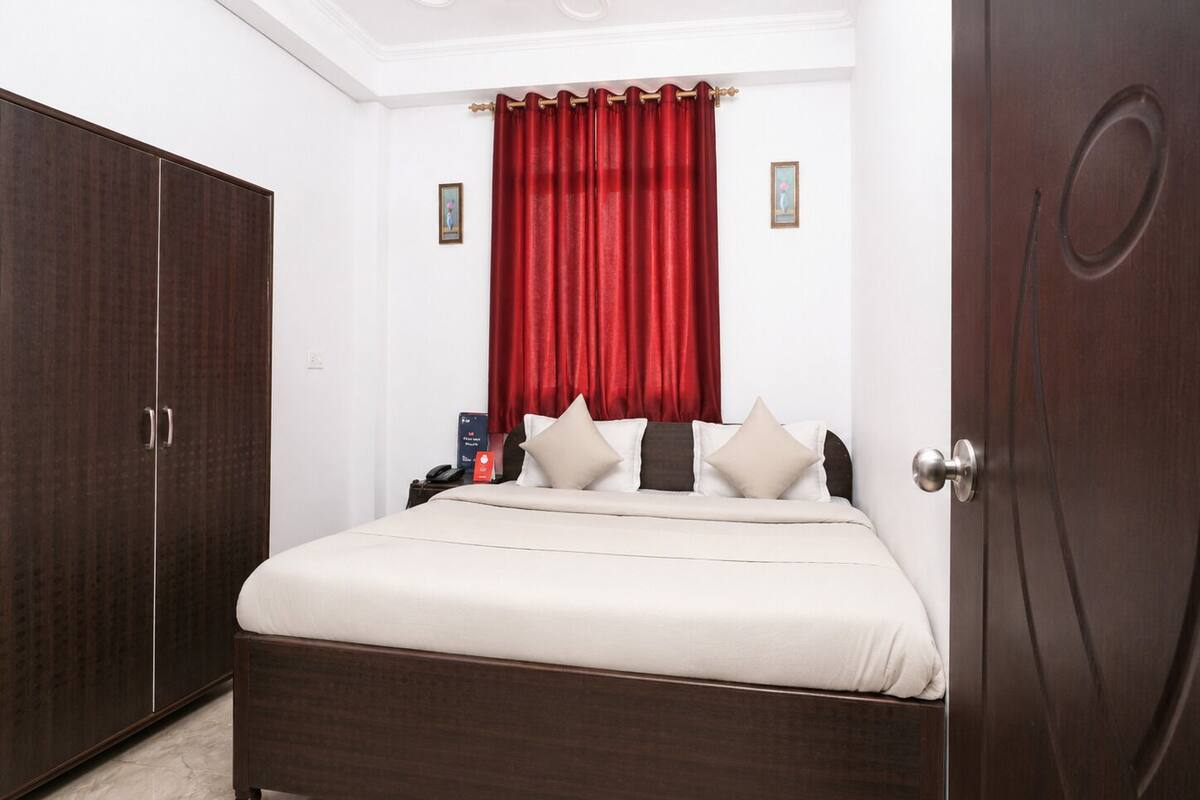 A bedroom with a bed, a wardrobe, a nightstand, and a red curtain.