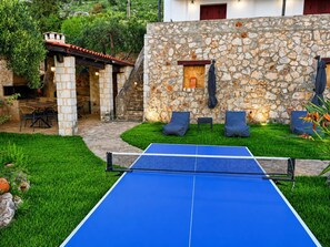 Ein Gartentischtennis-Tisch in einem Garten mit Steinmauern und Gartenmöbeln.