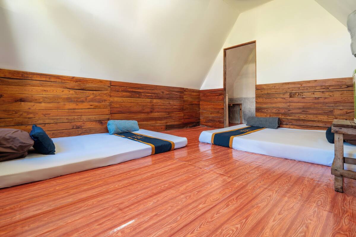 A room with two single beds, wooden walls, and a wooden floor.