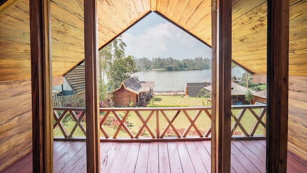 A wooden deck with a view of a lake and surrounding buildings. - TB Villa Resort By ARBA (Pangalengan)