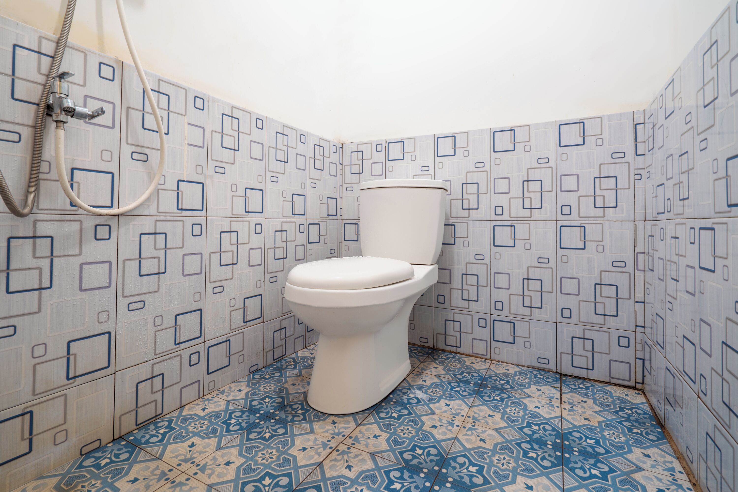A bathroom with a toilet, shower, and patterned tiles.