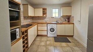 Eine kompakte Küche mit ein eingebautem Backofen, Mikrowelle, Waschmaschine und einem kleinen Fenster.