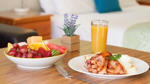 Et morgenbord med frugt i en skål, æg og bacon på en tallerken samt et glas appelsinjuice.
