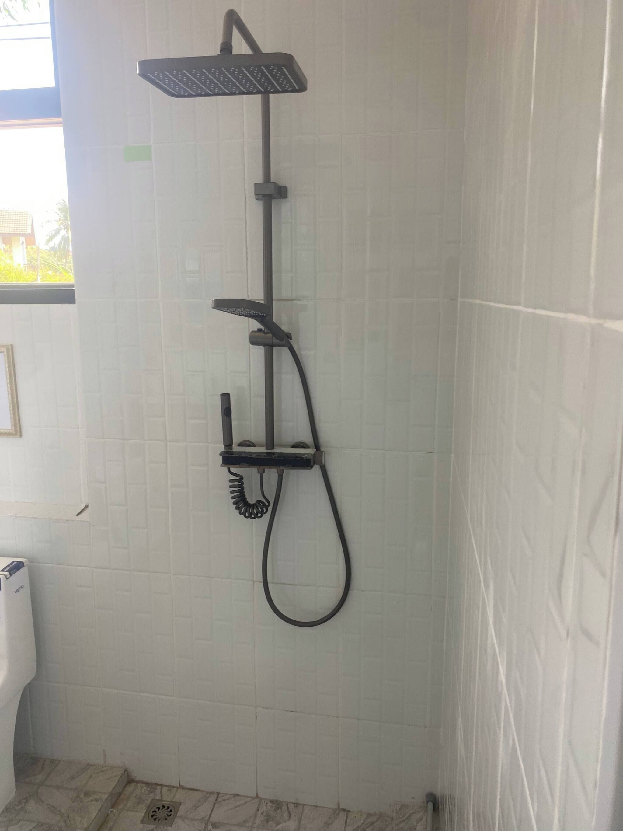 A shower with a handheld showerhead and a wall-mounted faucet.