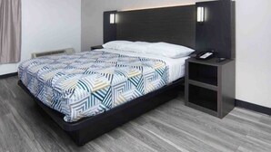 A modern hotel room with a bed, bedside tables, and a wall-mounted TV.