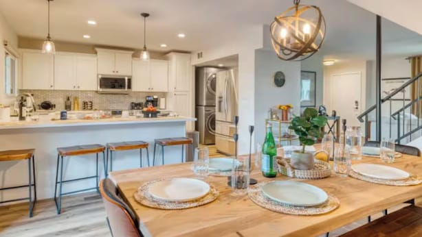 A modern kitchen with white cabinets, a central island, bar stools, and a dining table set for four. - Awesome 4-bedroom townhome with AC in sunny Scottsdale (Scottsdale)