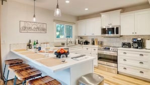 A modern kitchen with white cabinets, a central island, a stainless steel oven, and a hanging light fixture. - Awesome 4-bedroom townhome with AC in sunny Scottsdale (Scottsdale)
