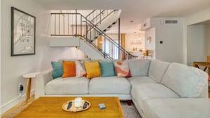 A living room with a sofa, a coffee table, a staircase, and a dining area in the background. - Awesome 4-bedroom townhome with AC in sunny Scottsdale (Scottsdale)