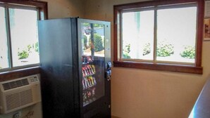 A kitchen with a refrigerator, a window, and a wall-mounted air conditioner.