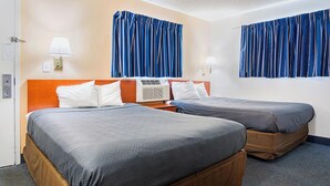 Ein Hotelzimmer mit zwei Betten, einer Wandklimaanlage und Vorhängen.