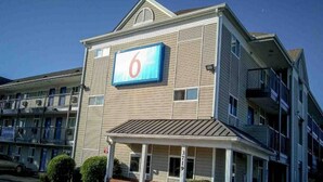 A motel with a prominent '6' sign, a covered front porch, and a brick foundation. - 2 Full Beds|Nsmk|Kitchen (Fayetteville)