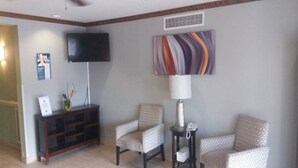 A hotel lobby with a television, a patterned wall art piece, a lamp, and two patterned chairs. - 1 King Bed|Non-Smoking,Kitchen (Myrtle Beach SC)