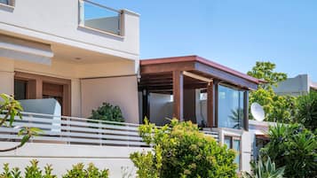 Ein modernes, zweistöckiges Haus mit Balkon, Satellitenschüssel und üppiger Bepflanzung.