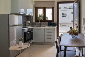 Eine moderne Küche mit Einbauofen, Kaffeemaschine und Essbereich mit Tisch und Stühlen.