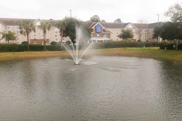 A hotel with a fountain in the courtyard, surrounded by greenery and a large building with a prominent logo. - 1 Queen Bed|Non-Smoking, Kitchen (Myrtle Beach SC)