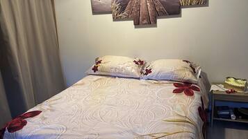 Une chambre à coucher comprenant un lit, une table de chevet, une lampe et une œuvre d’art accrochée au mur.