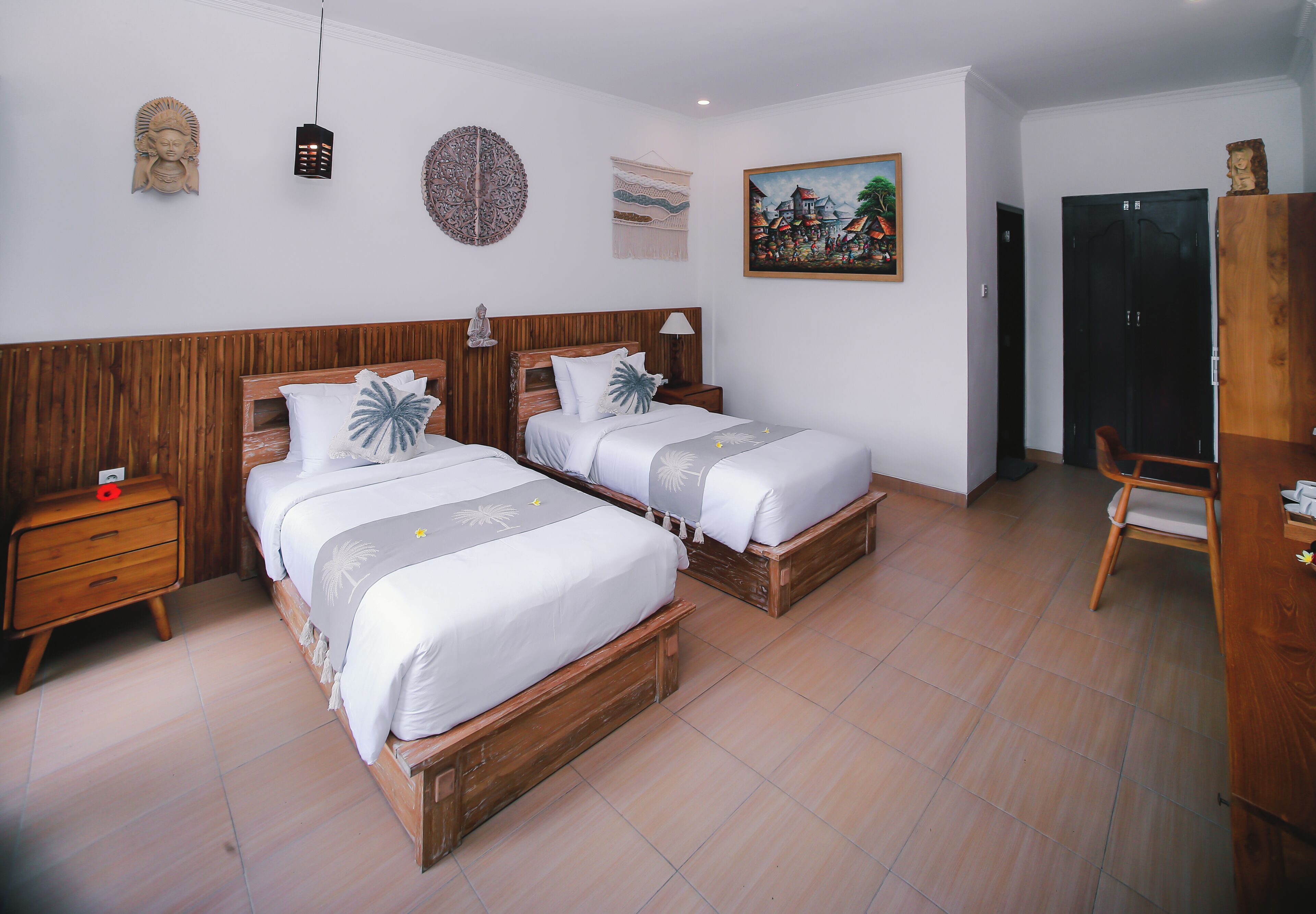 A room with two wooden beds, a wooden nightstand, a desk, and a chair.