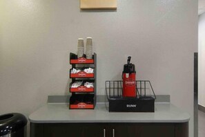 A counter with a coffee machine, disposable cups, and a Bunn coffee maker.