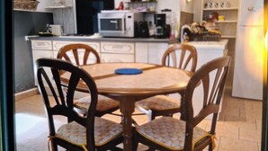 A kitchen with a dining table and chairs, a microwave, a refrigerator, and various kitchen appliances. - House in the Cevennes (Molières-sur-Cèze)
