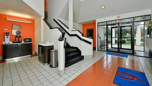 Eine Hotelhalle mit Treppe, Rezeption und Ausgangstür.