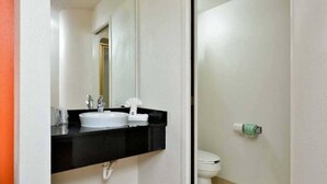 Ein Badezimmer mit einem weißen Waschbecken, einer schwarzen Arbeitsplatte und einem WC mit einem grünen Toilettenpapierhalter.