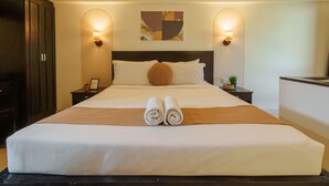 A hotel room with a large bed, two bedside tables, a headboard, and wall-mounted lighting. - Cove Premisol (Denpasar)