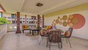 A spacious balcony with a dining area, including a table and chairs, and a decorative wall with circular patterns. - Cove Premisol (Denpasar)