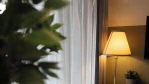 Une pièce avec une lampe, une plante, une table sur laquelle se trouve une assiette de nourriture et une tasse.