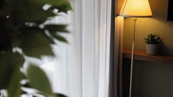 A room with a lamp, a plant, a table with a plate of food, and a cup.