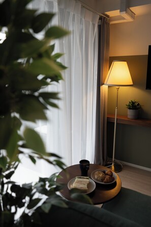 A room with a lamp, a plant, a table with a plate of food, and a cup. - Premiage Minoshima (Hakata Ward, Fukuoka)