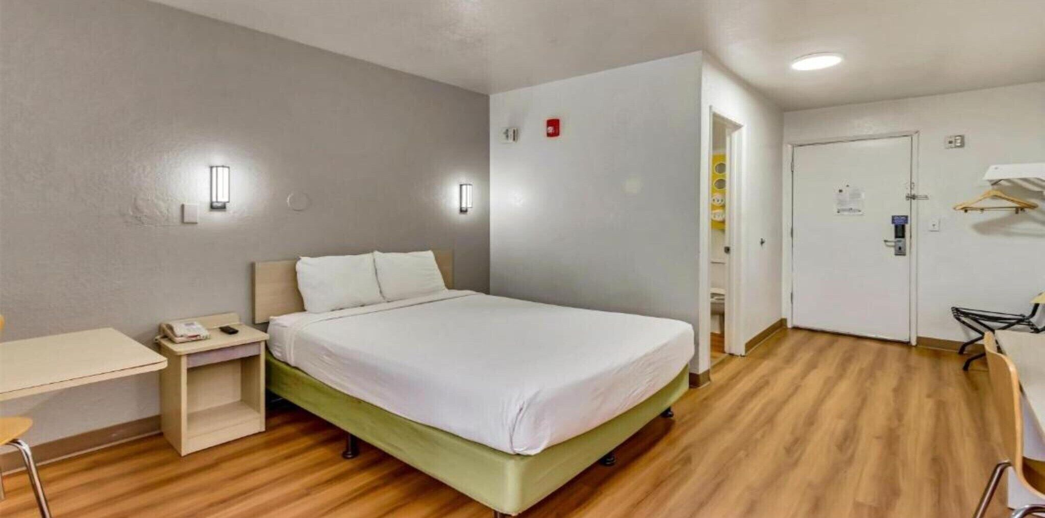 Une chambre d’hôtel comprenant un lit, une table de chevet, un bureau et une armoire.