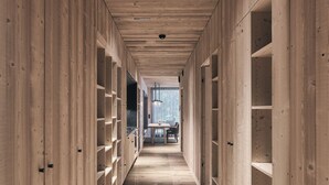 Un long couloir étroit aux murs et au sol en bois, qui mène à un espace repas avec une table et des chaises.
