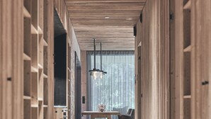 Un long couloir étroit aux murs et au plancher en bois, qui mène à un espace repas comprenant une table et des chaises.