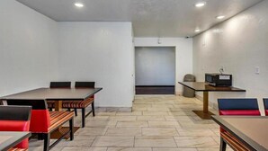 Une salle de conférence avec une grande table, plusieurs chaises, une petite table avec un ordinateur et une poubelle.
