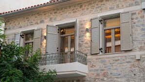 Ein Gebäude aus Stein mit Fensterläden, einem Balkon und einem kleinen Garten.